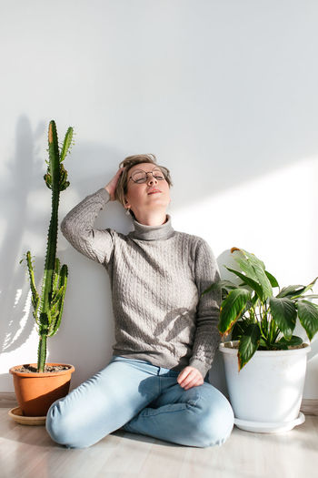 Man sitting on potted plant at home