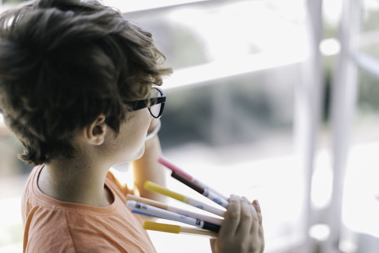 High angle view of boy holding colored pencils