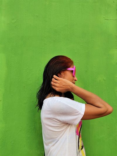 Rear view of woman standing against green wall