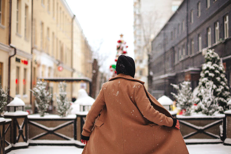Rear view of woman standing in city during winter