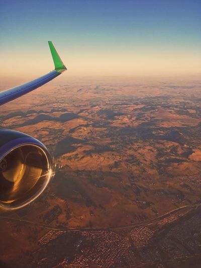 Aerial view of airplane wing over landscape against sky