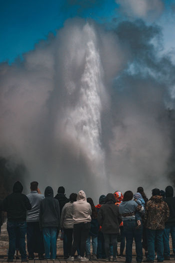 People standing against the old faithful geyser. 