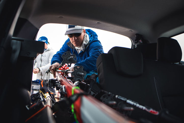 A man pulls skis out of the backseat of an suv