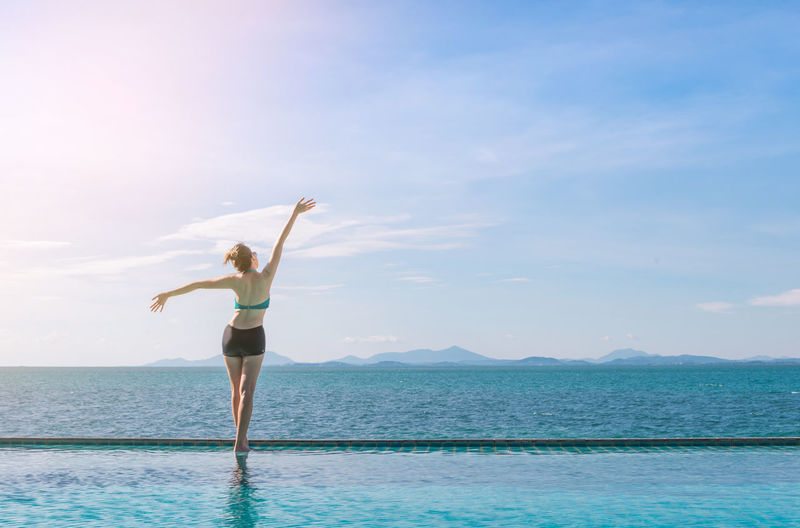Woman standing by sea against sky