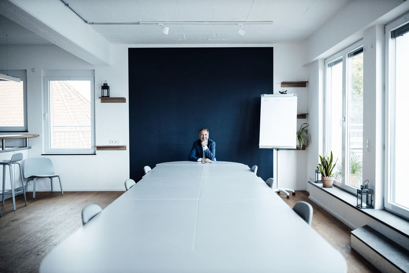 Male entrepreneur with hand on chin while sitting in board room
