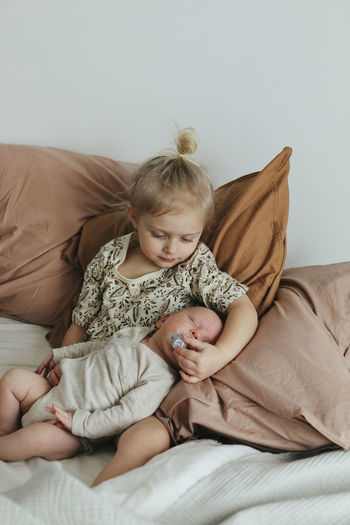 Girl with newborn sibling on bed