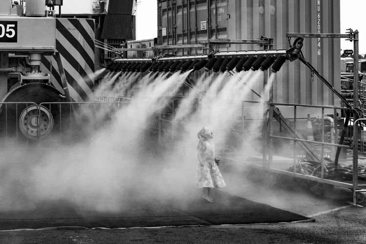 A little girl plays in water mist at the cooks wharf open day in auckland new zealand. 2018