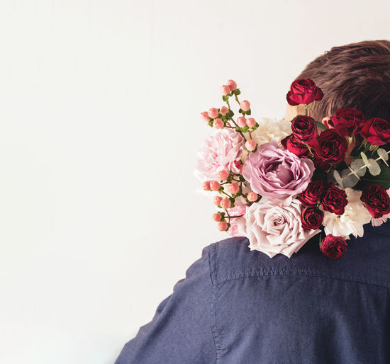 A man in a shirt from the back. person holding a bouquet of flowers on his shoulder. 