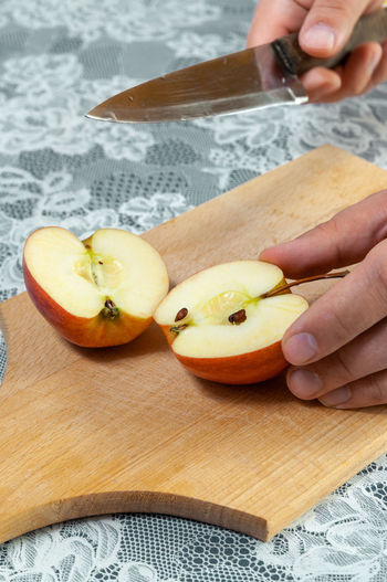 Midsection of person holding apple on cutting board