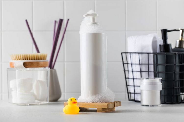Bottle of cosmetic product and toy duck with different toiletries on countertop