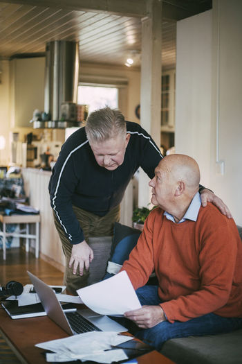 Senior gay couple calculating financial bills in living room at home