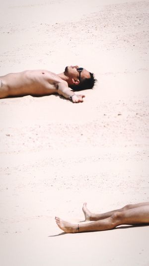 Shirtless man lying on sand