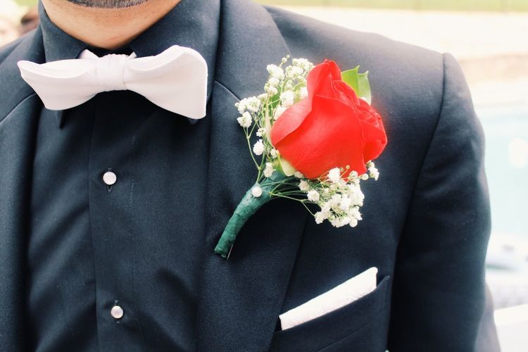 Midsection of man with red boutonniere