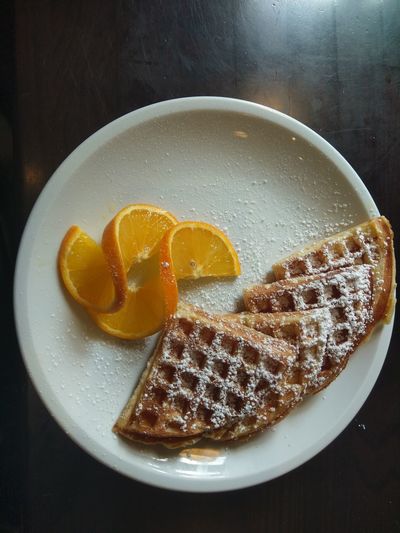 Tasty waffle with sugar and orange slices