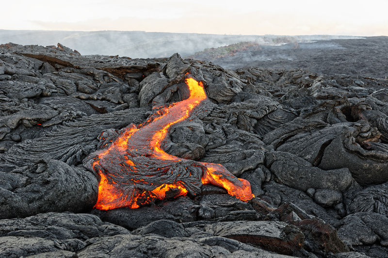 Active lava flow on hawaii, magma emerges from a fissure, slowly cooling and solidifying in patterns