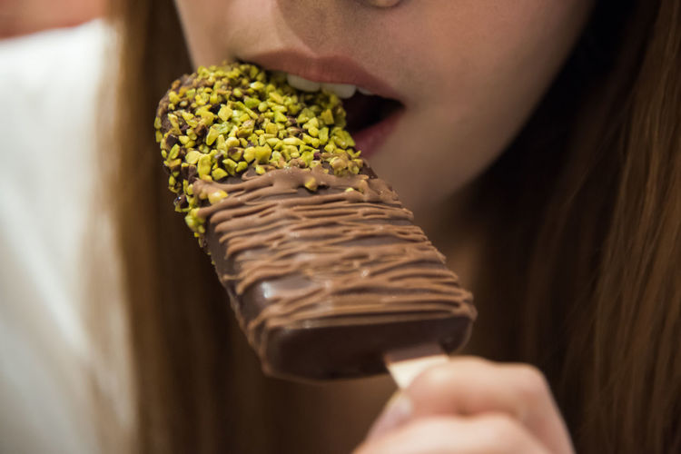 Cropped image of woman eating ice cream bar