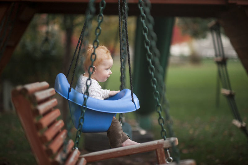 Cute baby boy swinging at park