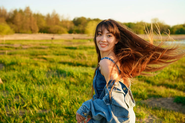 Portrait of a beautiful young woman with fluttering hair in nature