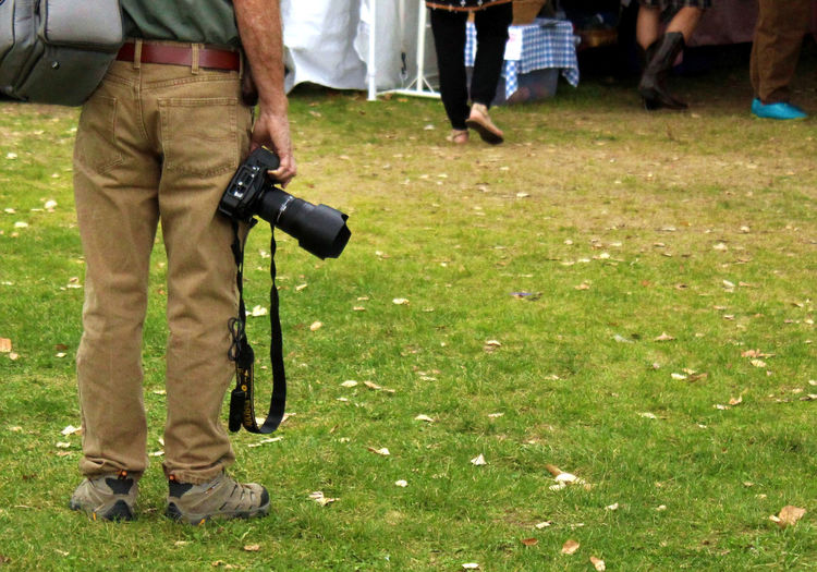 Photographer standing with camera at side
