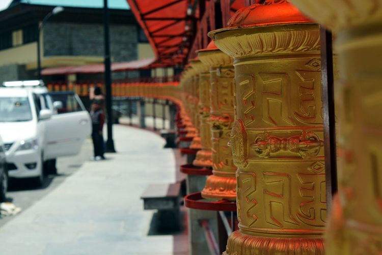 Golden prayer wheels by sidewalk in town