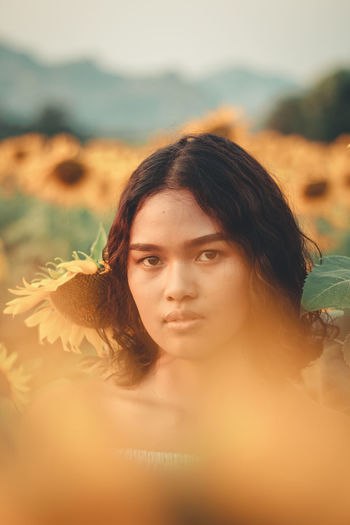 Portrait of young woman standing at sunflower farm