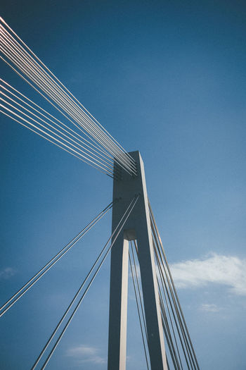 Low angle view of suspension bridge against blue sky
