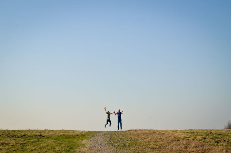 PEOPLE STANDING ON FIELD AGAINST SKY