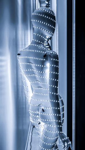 Midsection of woman standing by illuminated window