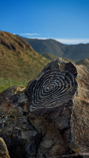 Close-up of rock on land against sky petroglyphs 