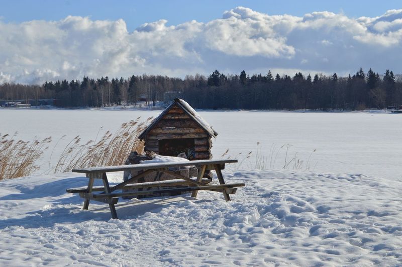 Hut on snow field against sky