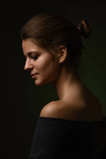 Side view of young woman against black background