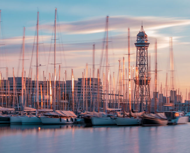 Sailboats in sea at harbor against sky during sunset