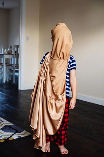 Woman covering face while standing on wooden floor at home