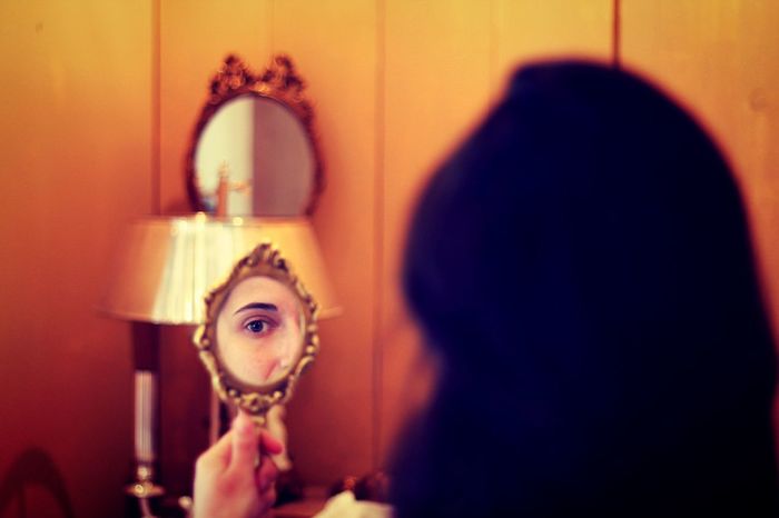 Close-up of a beautiful young woman looking at mirror