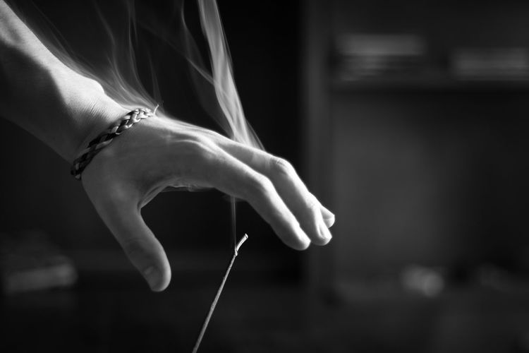 Cropped hand of woman over burning incense