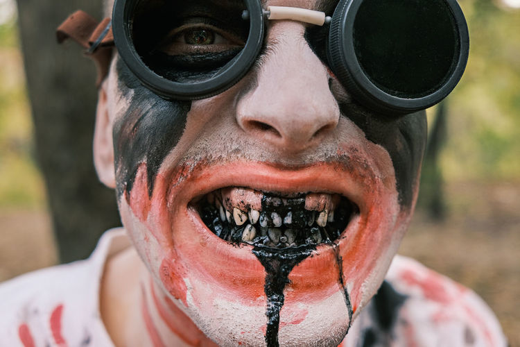 Close-up portrait of face of zombie with traces of blood and black fluid flowing from the mouth. 