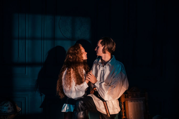 Young couple standing against wall at night
