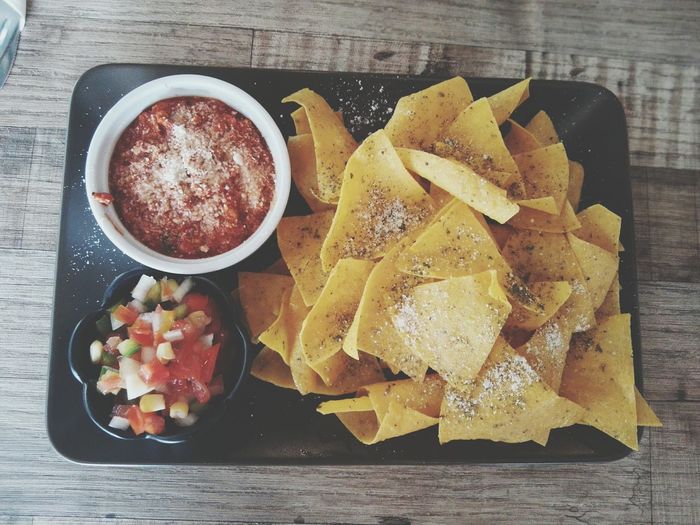 Close-up of nachos and sauce served in plate on table