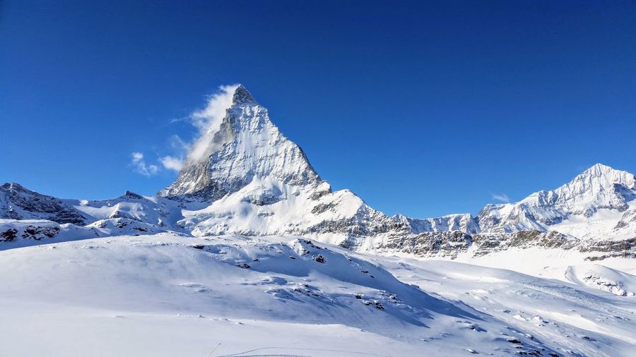 Scenic view of snowcapped mountains against clear blue sky