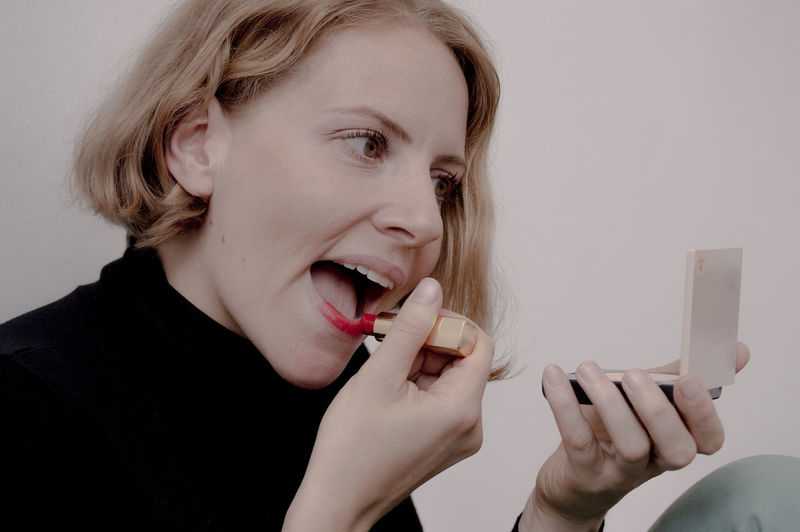 Beautiful woman applying red lipstick