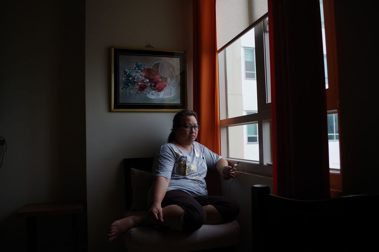 Portrait of woman sitting by window at home