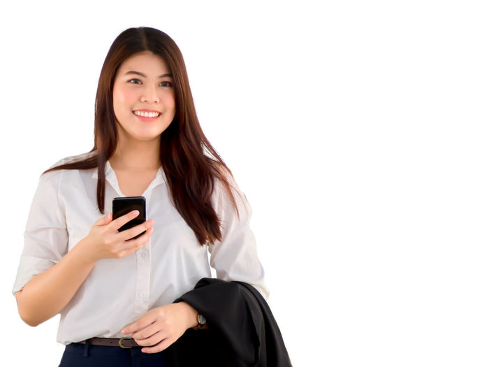 Smiling young woman using smart phone against white background