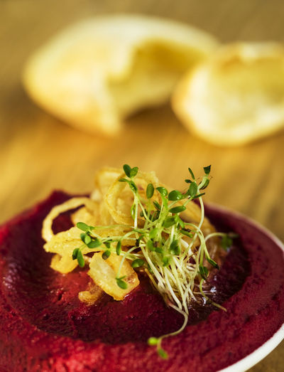 Close-up of beetroot hummus with sprouts in bowl on cutting board