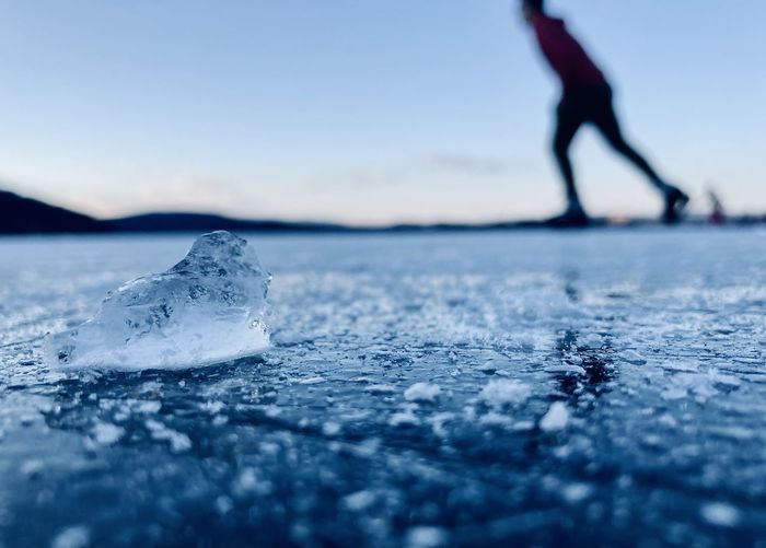 Low section of person on frozen sea against sky