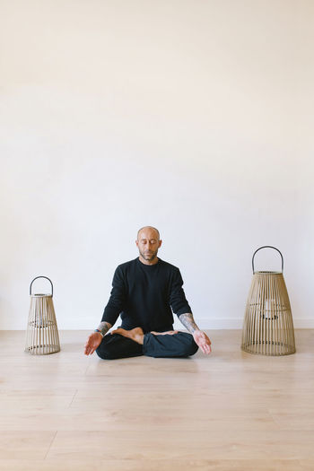 Man sitting in lotus position meditating at yoga studio