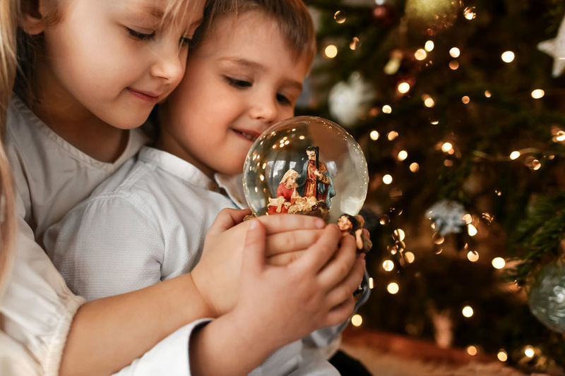 The kids looking at a glass ball with a nativity scene of the birth of jesus christ
