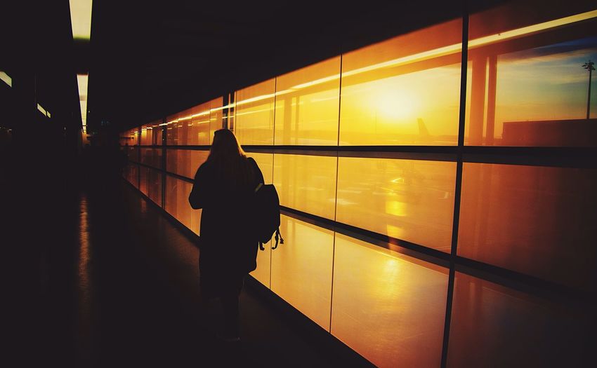 Rear view of woman walking in airport during sunrise