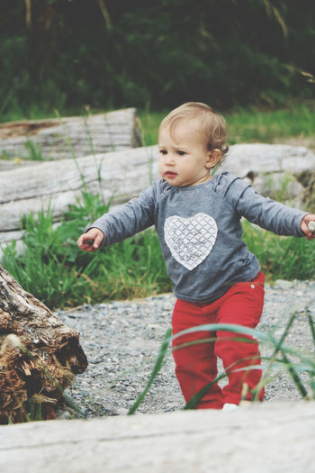 Portrait of cute baby boy standing by tree trunk