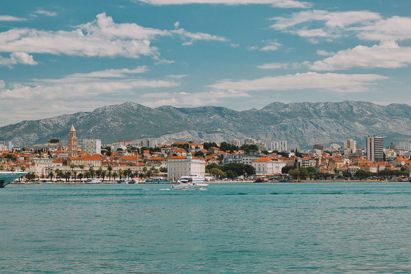 Scenic view of sea by townscape against sky