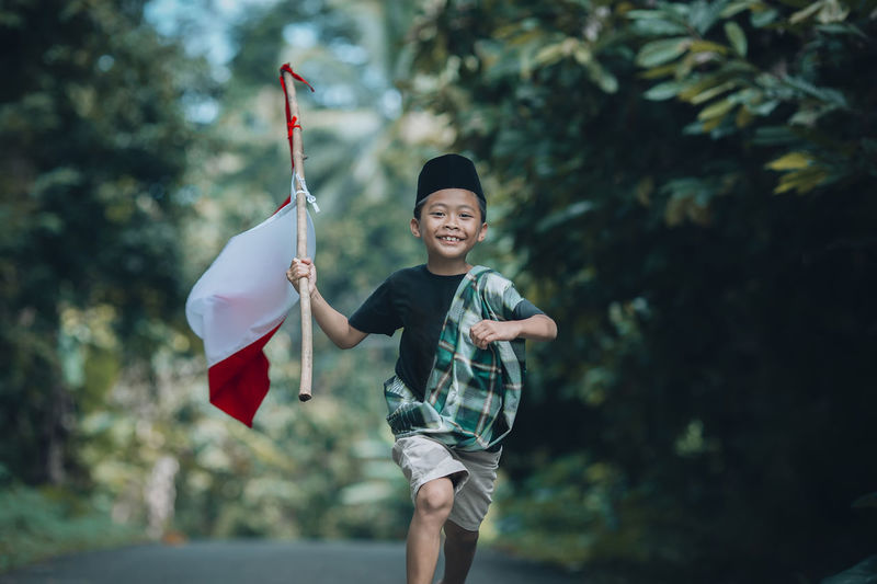 Portrait of kid running holding indonesian flag